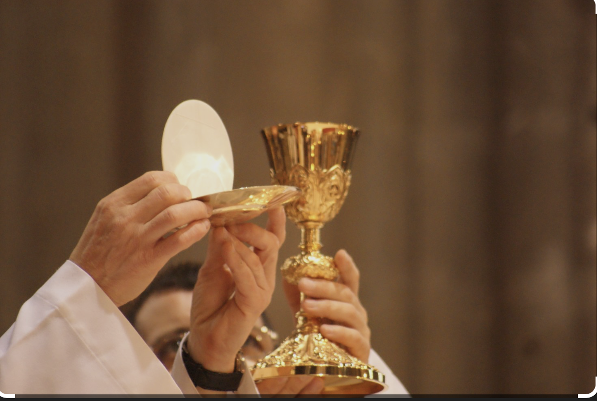 Prêtre élevant l'hostie et le calice lors de la consécration de la Sainte Messe